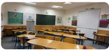 Sală de clasă amenajată cu tablă și bănci